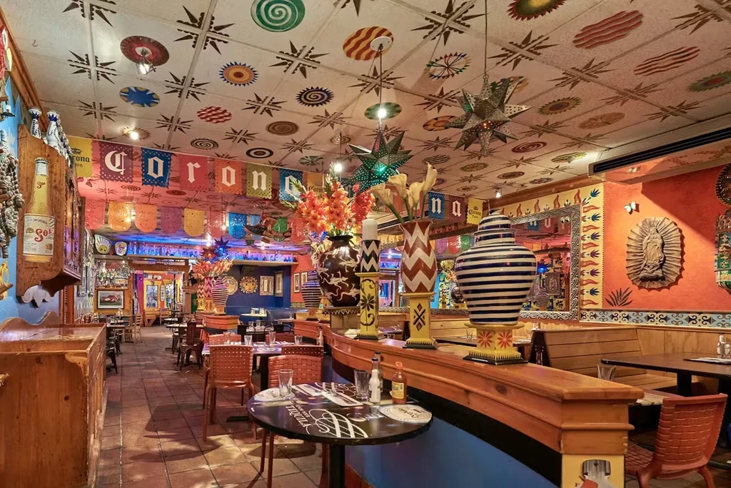 A brightly decorated Mexican restaurant with colorful ceiling art and festive banners.