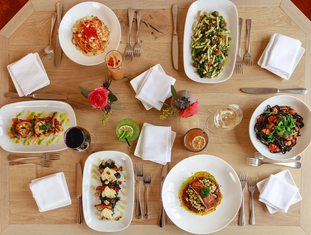 Overhead view of a wooden table set with multiple Italian dishes.