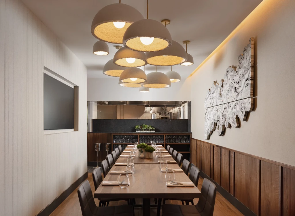 A long dining table beneath unique pendant lights in a modern restaurant.