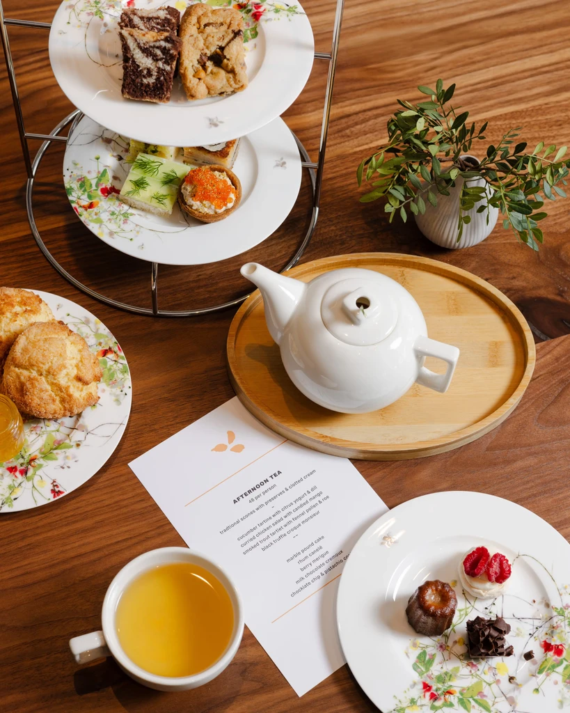 Overhead view of an afternoon tea spread on a wooden table.