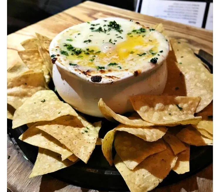 A ramekin of baked eggs with cheese and tortilla chips.