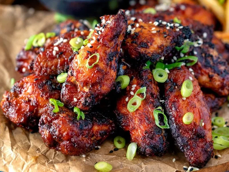 Close-up of baked chicken wings with sesame seeds and green onions.