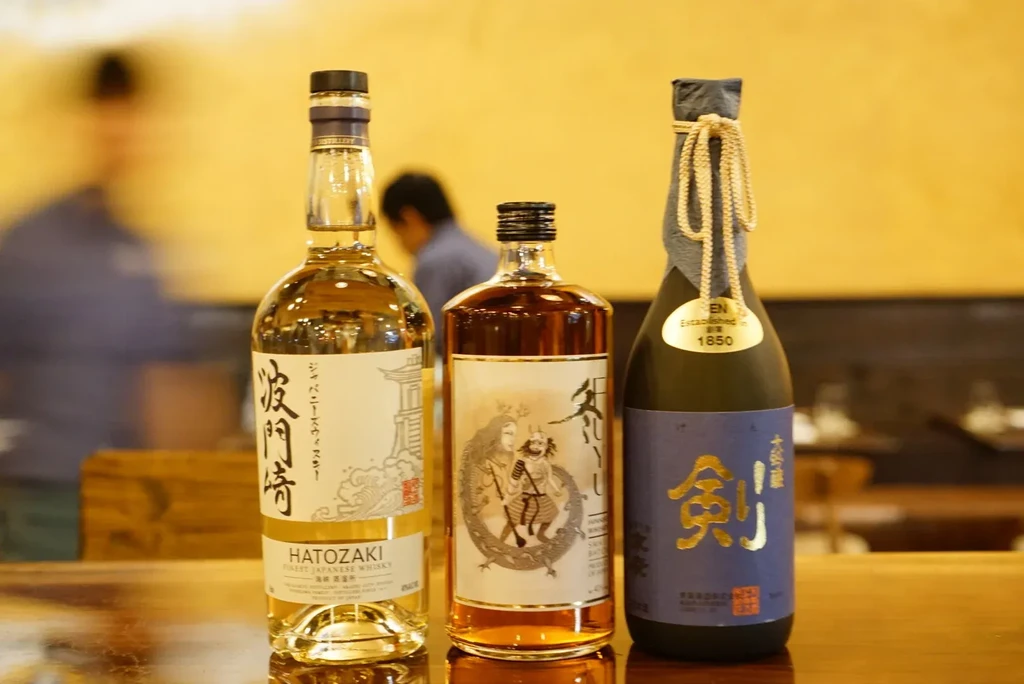 Three bottles of Japanese whisky and sake on a bar counter.