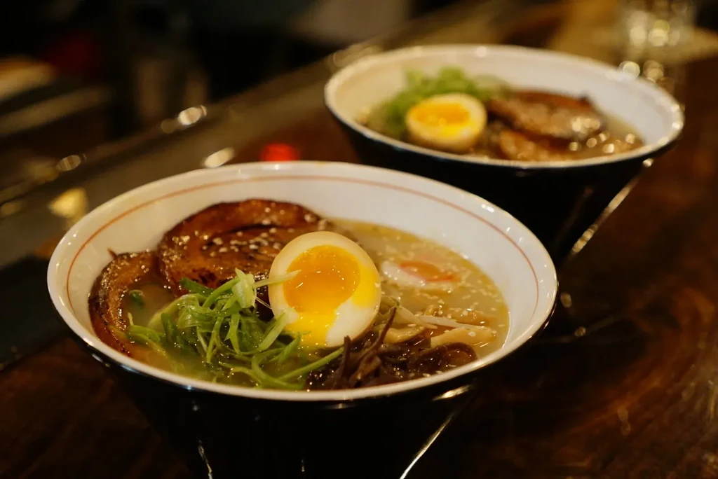 Two bowls of ramen with soft-boiled eggs and pork belly.