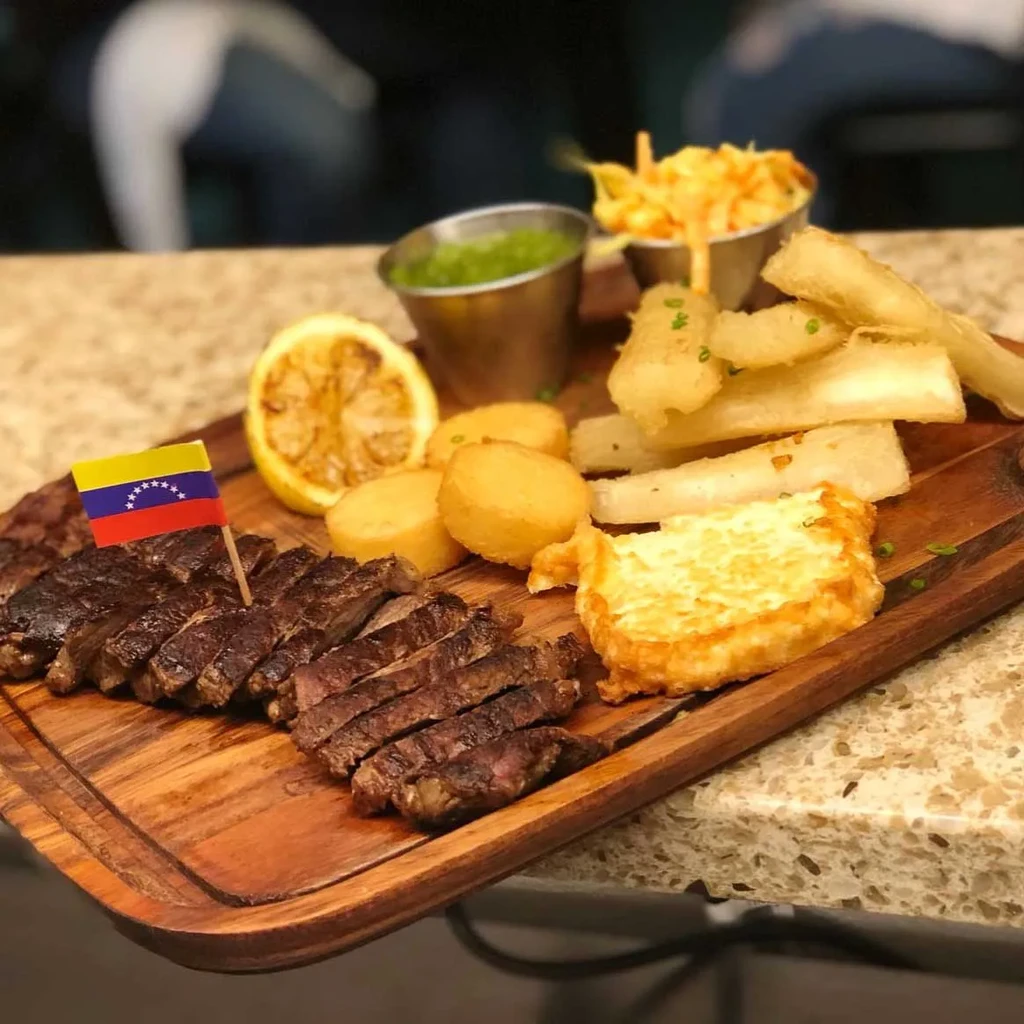 Venezuelan steak, fried potatoes, yuca, and cheese on a wooden board.