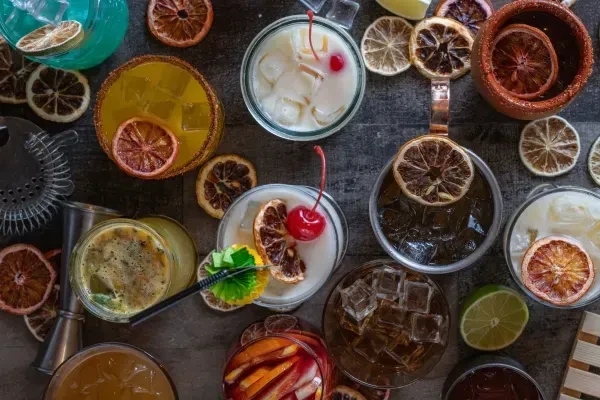 Overhead view of several garnished cocktails and dried citrus slices on a table.