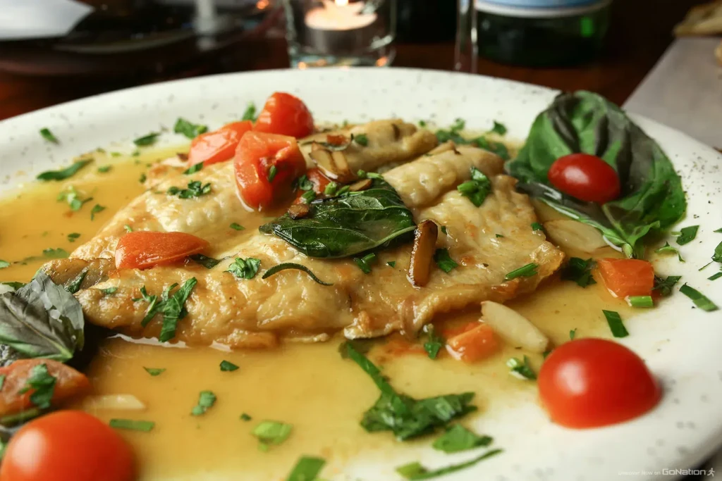 Italian dish with cooked ravioli, cherry tomatoes, and basil in sauce.