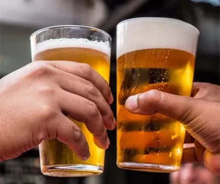Two hands holding glasses of golden beer, making a toast.