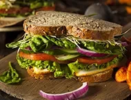 A large vegetarian sandwich with whole wheat bread, lettuce, and tomato.