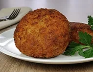 Close-up of a golden-brown deep-fried arancino on a white plate.