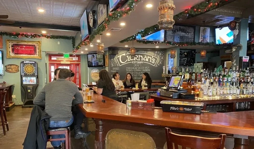 People seated at a lively bar with many screens and festive decorations.