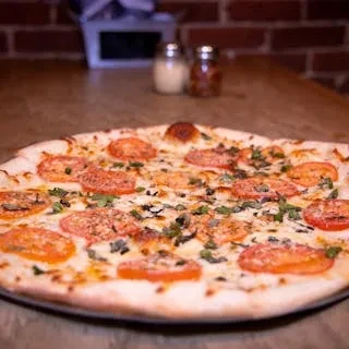 A round Margherita pizza topped with sliced tomatoes and basil.