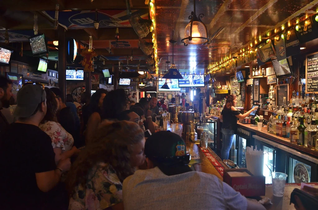 Crowded, dimly lit bar with a bartender and patrons.