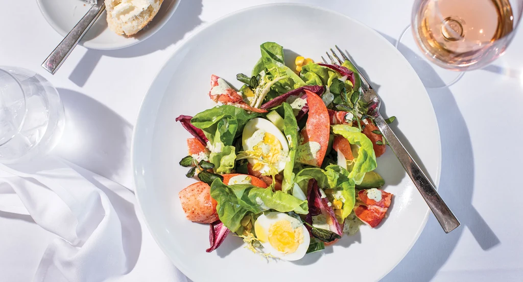 A lobster salad with hard-boiled egg on a white plate.