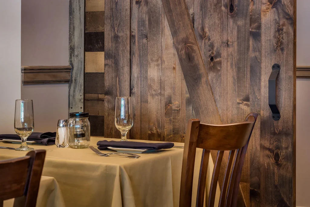 Rustic restaurant table set for two with barn door background.