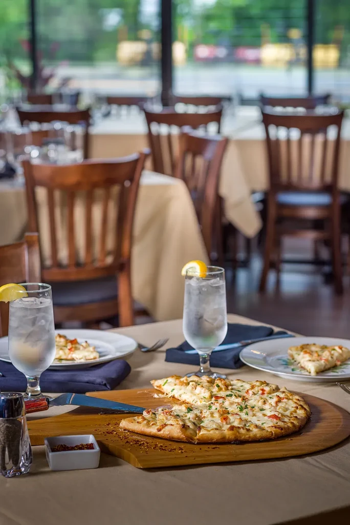 Sliced flatbread with cheese, herbs, and water on a restaurant table.