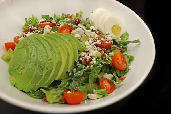 Vibrant salad with avocado, tomatoes, cheese, bacon, and hard-boiled egg.
