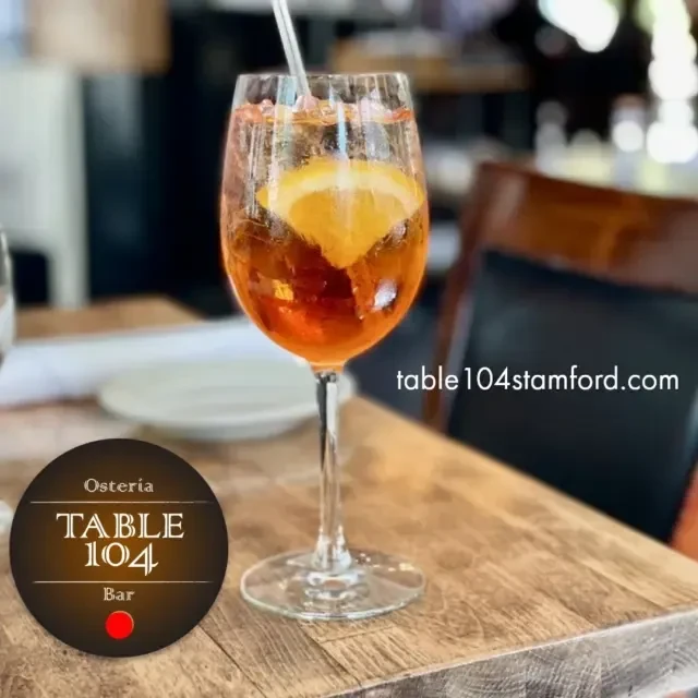 Orange spritz cocktail with an orange slice on a wooden table.