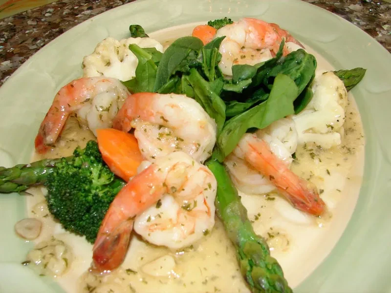 Shrimp with broccoli, cauliflower, carrots, asparagus, and spinach in sauce.