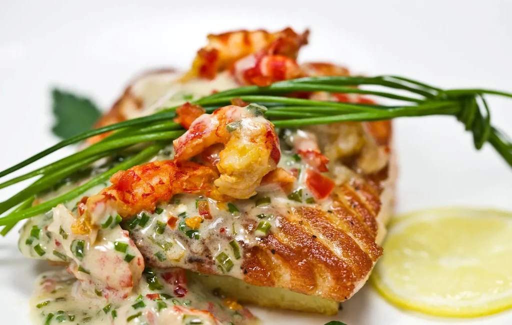 Grilled salmon with creamy sauce, crawfish, chives, and lemon slice.