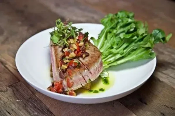 Seared tuna steak with chopped vegetables and green salad.