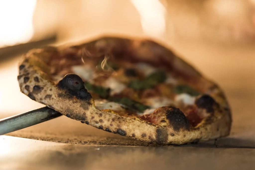 Steaming hot Neapolitan pizza with a charred crust pulled from the oven.