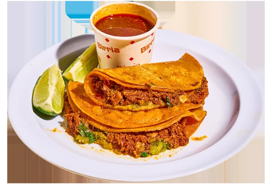 A plate with birria tacos, lime wedges, and a cup of consommé.