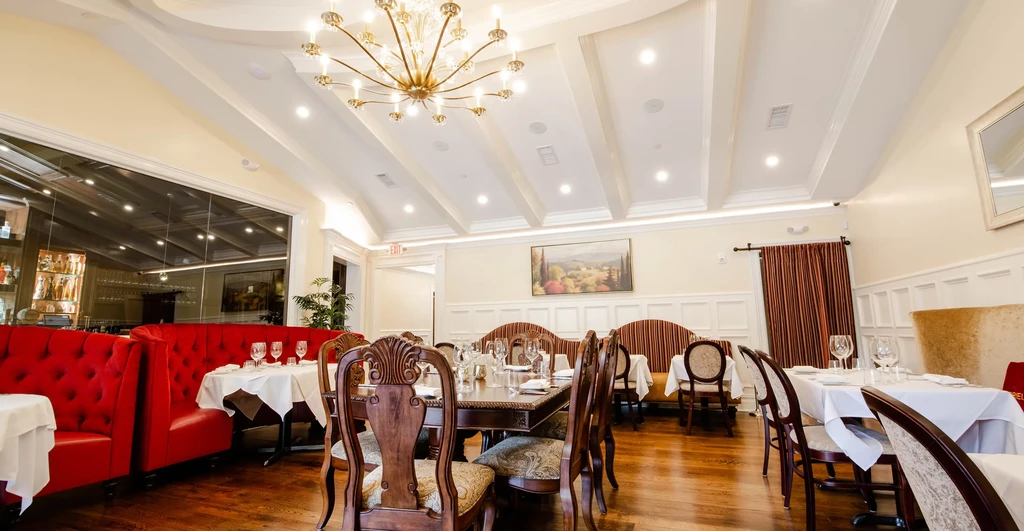 An elegant restaurant dining room with red booths and white tablecloths.