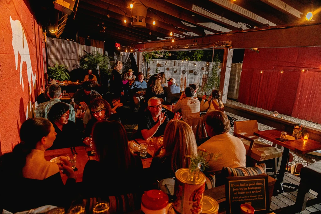 Warmly lit, crowded restaurant patio at night under string lights.