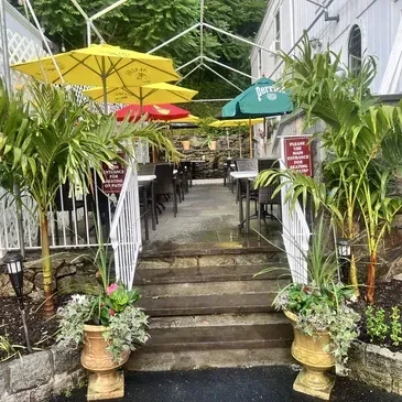 Outdoor restaurant patio with tables, plants, and yellow Perrier umbrellas.