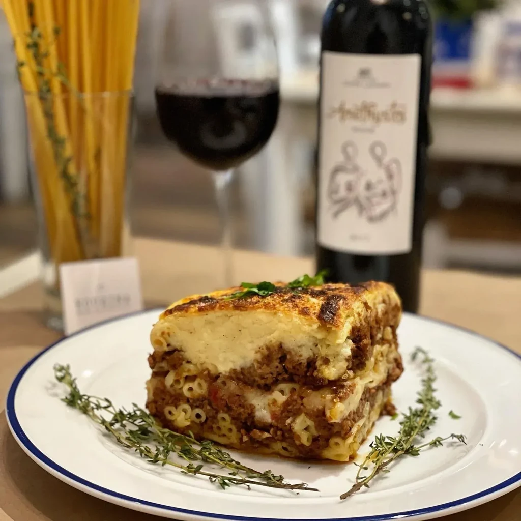 A serving of pastitsio with red wine, pasta, and herbs on a plate.