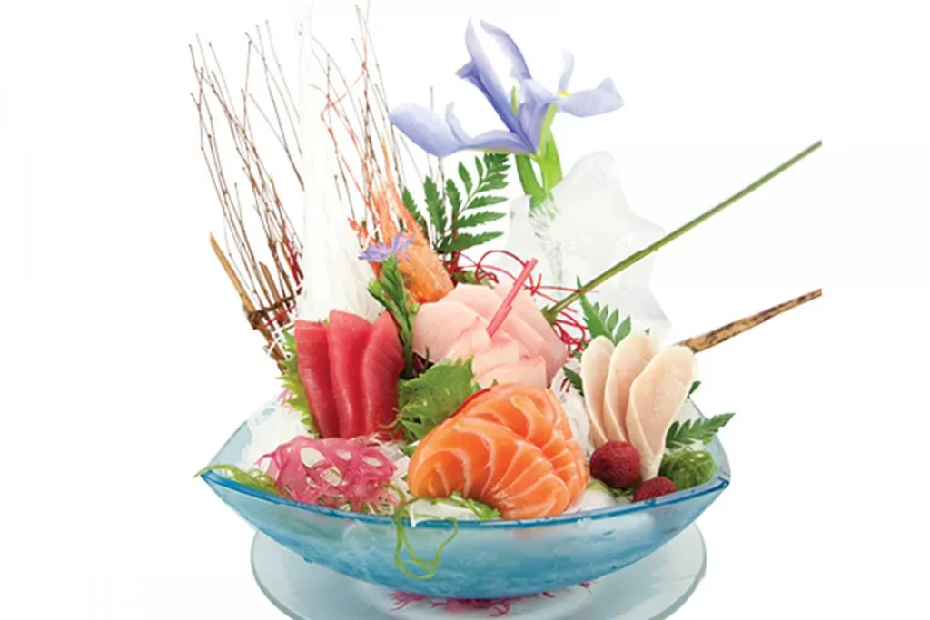 A boat-shaped platter of sashimi, garnished with an iris flower.