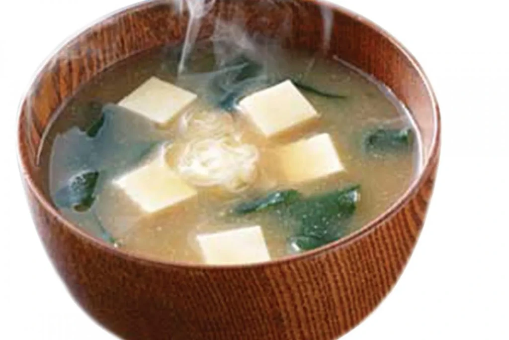Steaming hot bowl of miso soup with tofu and seaweed.
