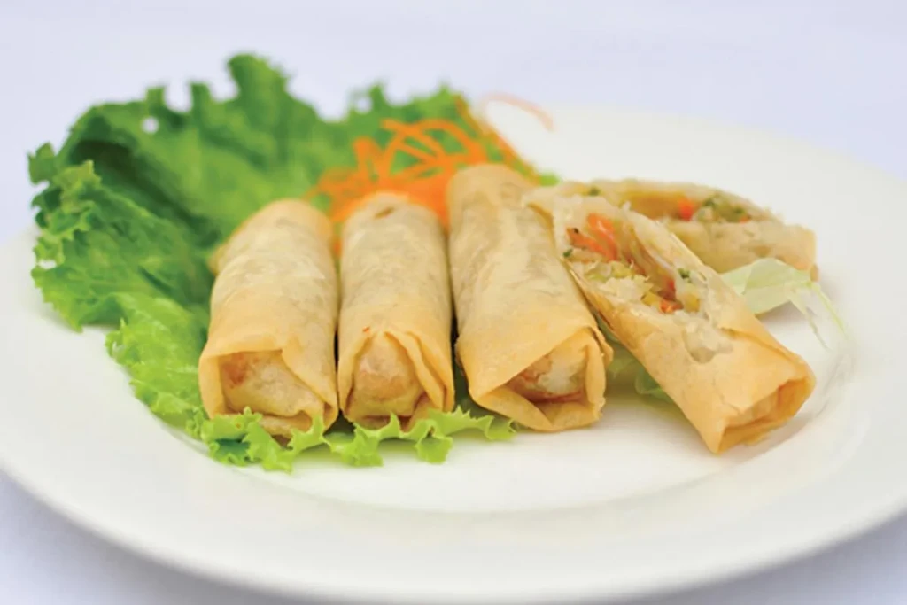 A plate of spring rolls, one cut open, with lettuce.