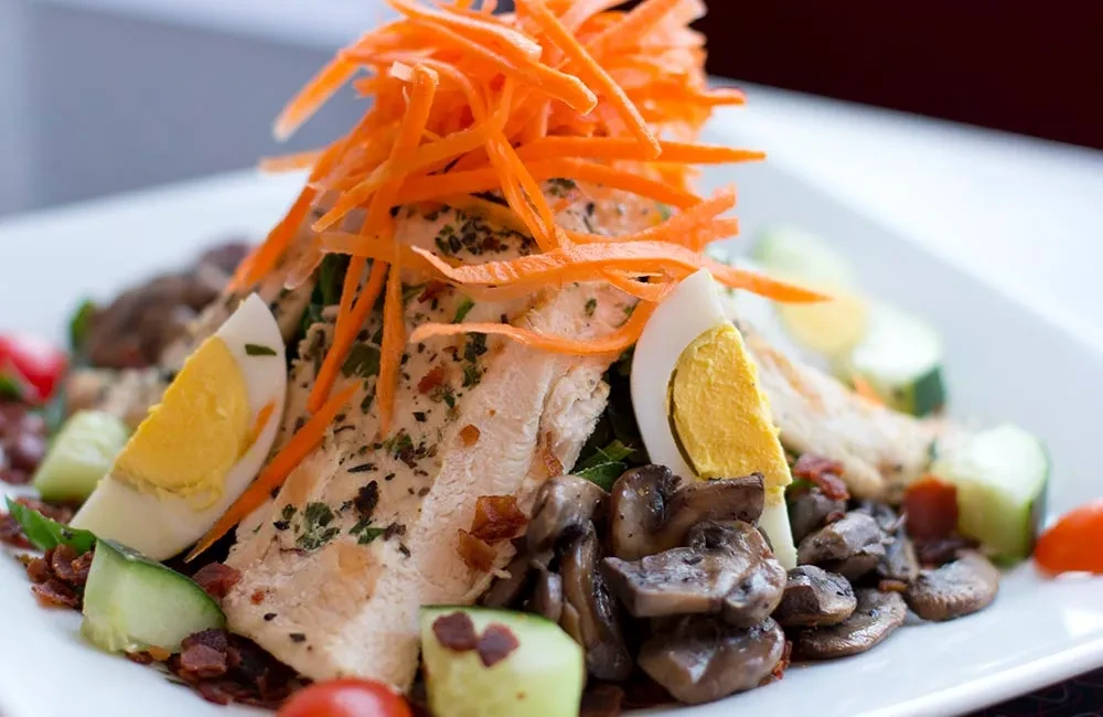 Chicken salad with shredded carrots, boiled eggs, mushrooms, and cucumbers.