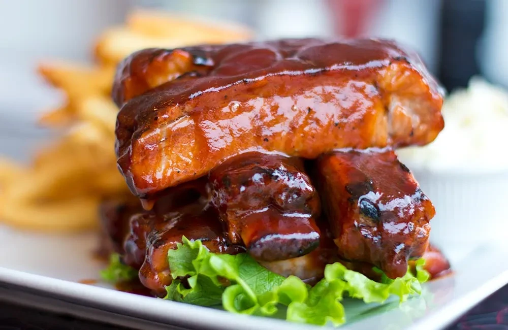 Ribs with barbecue sauce on a bed of lettuce, with fries.