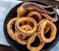 Fried calamari rings and a tentacle on a black plate.