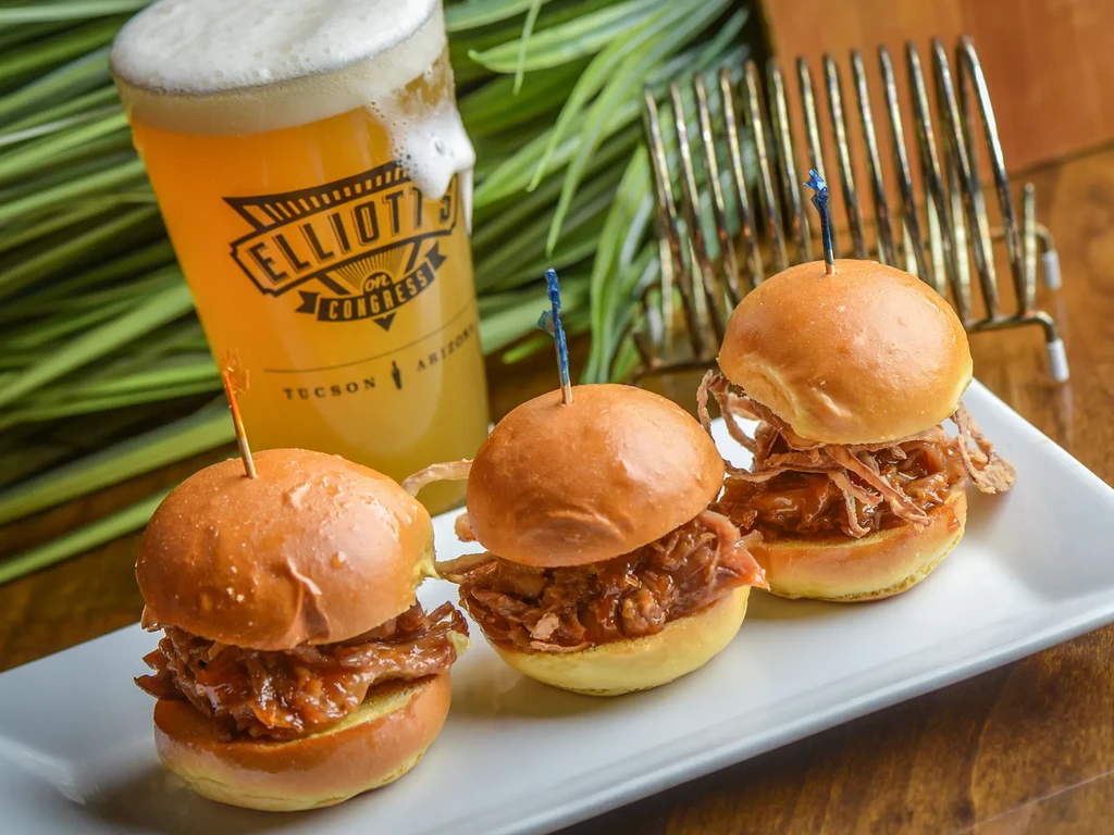 Three shredded meat sliders and frothy beer, branded Elliott's on Congress.