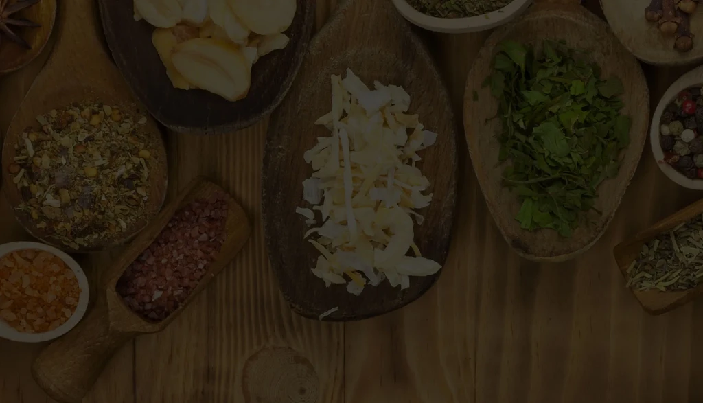 Meticulously arranged spices, herbs, and ingredients on a dark rustic wooden surface.