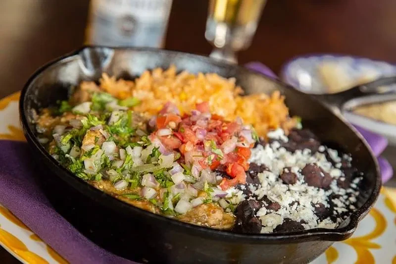 Mexican skillet meal with meat, pico, beans, and rice.