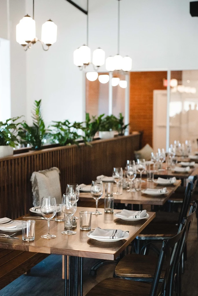 Modern restaurant interior with a long row of neatly set tables.
