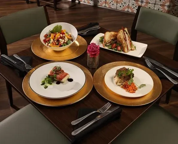 Four elegantly plated dishes on a restaurant table with gold chargers.