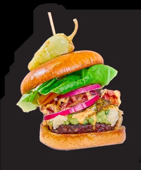 Detailed gourmet burger with guacamole, bacon, red onion, and shishito pepper.