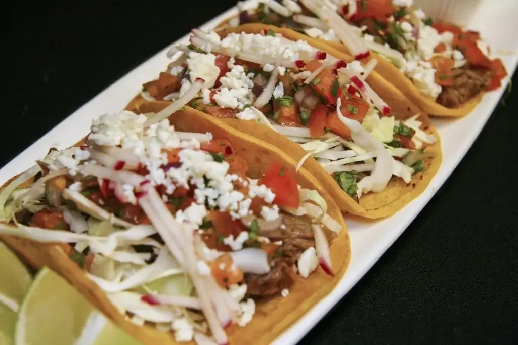 Four meat tacos with cabbage, pico de gallo, cheese, and lime.