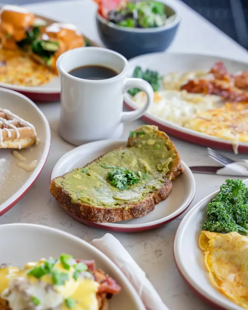 Overhead of avocado toast, coffee, and diverse brunch dishes.