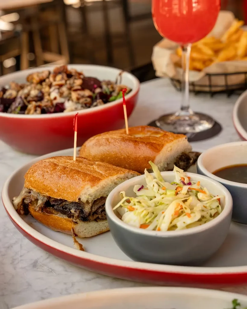 Toasted shredded meat and cheese sandwich, coleslaw, fries, and drink.
