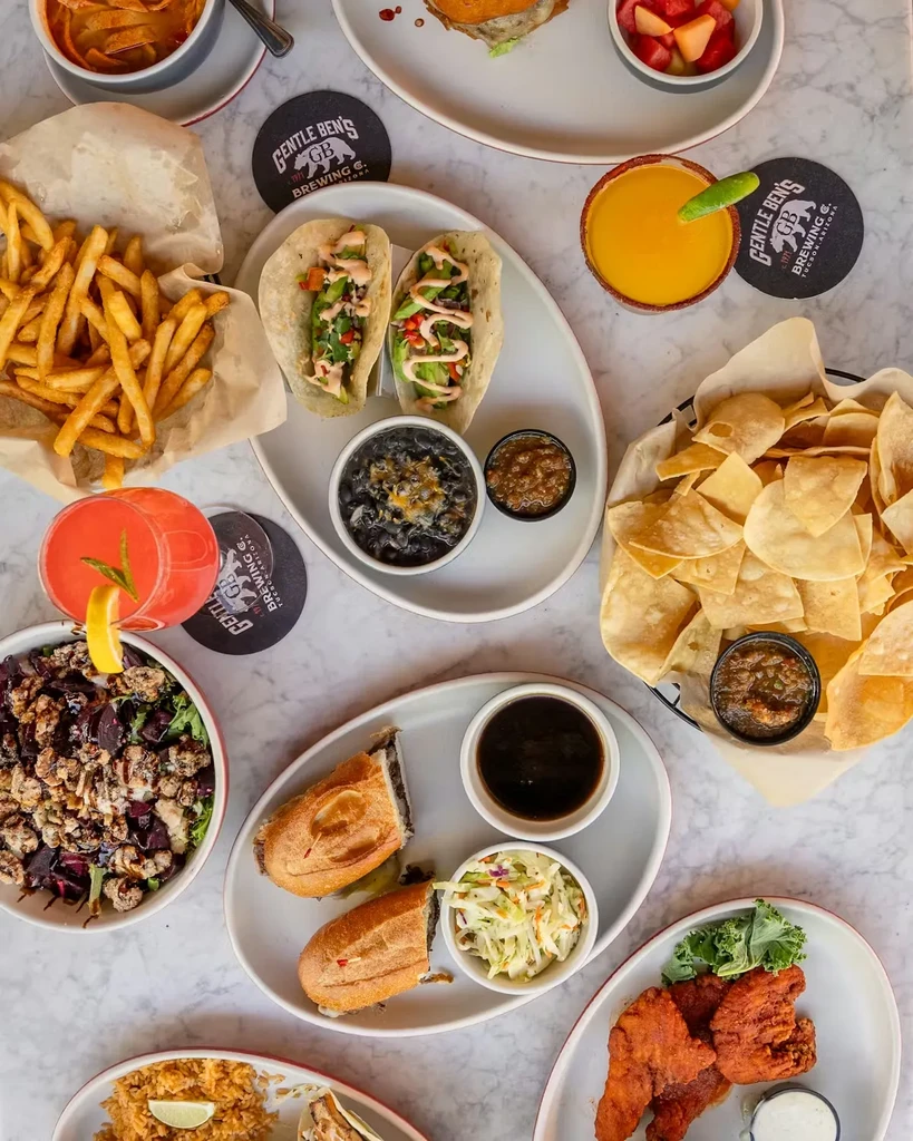 Overhead flat-lay of diverse restaurant dishes and cocktails from Gentle Ben's.