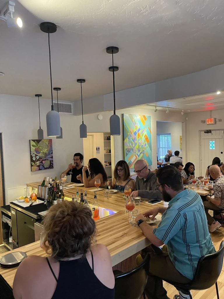 Patrons enjoy drinks and small plates at a well-stocked modern bar.