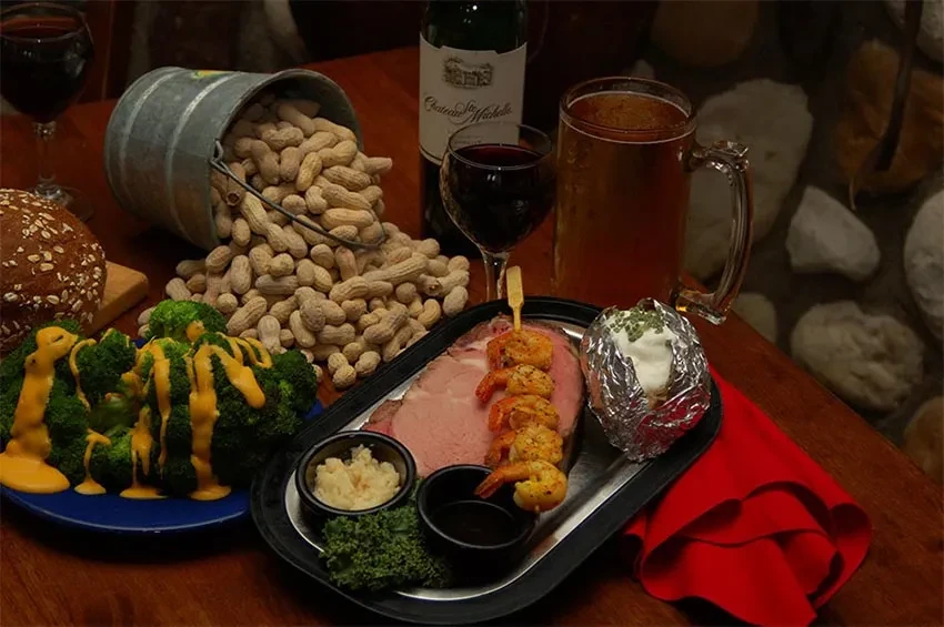 Hearty prime rib meal with shrimp, potato, peanuts, wine, and beer.