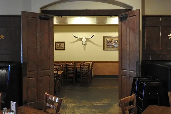 View through arched doorway to rustic restaurant with longhorn skull decor.